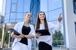 © RomanR - Happy women in business suits with folder standing before big business office