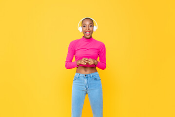 Fashionable African American woman with headphones smiling on colorful yellow isolated studio background