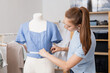 © Parilov - Seamstress woman takes measurements from mannequin with measuring tape, sewing clothes