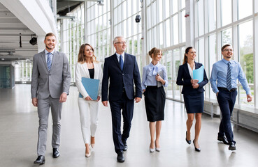 Wall Mural - people, work and corporate concept - business team with folders walking along office building and talking