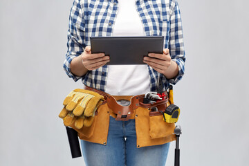 repair, construction and building concept - woman or builder with tablet pc computer working tools on belt over grey background