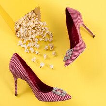 Luxurious Red Checkered High-heeled Shoes With Buckle Brooch With Crystals, Scattered Popcorn On A Yellow Paper Background, Shoe Advertising, Banner, Mock-up
