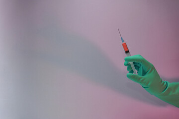 Poster - Beautiful hand holding creative syringe with red vaccine in the neon light. Minimalism retro style concept. Background pattern for design...
