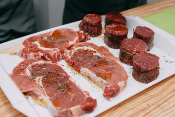 Aged beef for cooking steak in a cooking class. Raw beef and greens, close-up.