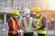 © saravut - Asian man civil engineer architect wearing safety helmet meeting at contruction site.Architecture engineering teamwork meeting at workplace