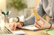 © PheelingsMedia - Student hands holding snack bar using laptop