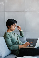 Sticker - Image of asian man working with laptop and documents while sitting