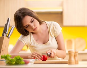 Young woman preparing salad at home in kitchen