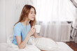 © Sviatlana - Beautiful girl drinking morning coffee sitting in bed. The girl is enjoying the morning, holding a Cup with a hot drink in her hands