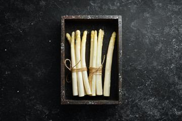 Raw white fresh asparagus on a black stone background. Healthy food. Top view. Free space for your text.