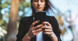 © A_B_C - Beautiful young business woman looking smart phone outdoors. close-up of hands of a girl who writes a message in a mobile phone, empty space for text.