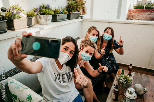 .Group of young girlfriends meeting after the quarantine caused by the covid pandemic19. Taking precaution with the use of surgical masks and taking the first photos together with a smartphone.
