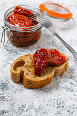 homemade organic sauce with dried tomatoes, olive oil and spices in a glass jar and an example of us