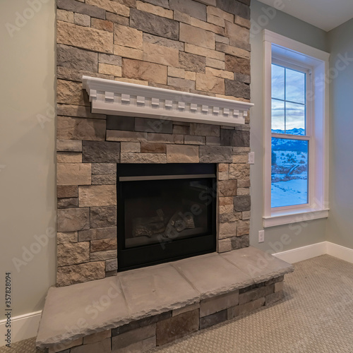 Square Modern fireplace and decorative shelf against stone brick accent wall of home