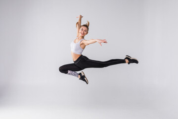 Happy young fitness woman jumping over white background