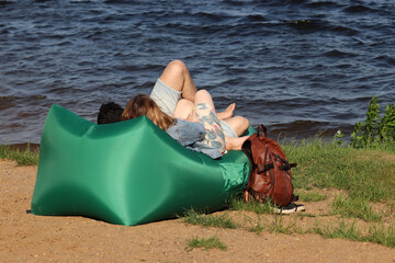 Love couple laying on inflatable sofa on a beach. Summer leisure and relaxation, romantic date on a wild nature