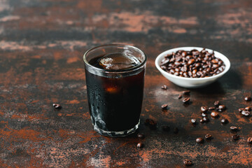 Wall Mural - selective focus of cold brew coffee with ice in glass near coffee beans on rusty surface