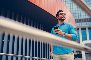 Handsome tourist chatting with best friend via phone while strolling in downtown
