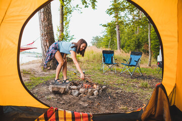 Wall Mural - view from camping tent woman cooking on burner near bonfire