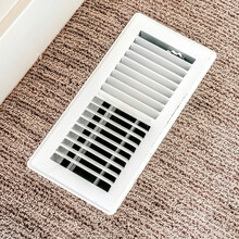 Square Frame White Air Conditioner Duct Grille Cover Against Floor With Brown Carpet
