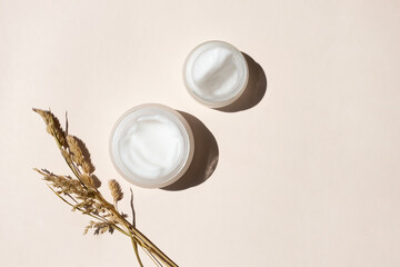 moisturizer creams and dry meadow herbs on beige background, top view. care for sensitive skin with 