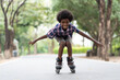© amorn - African American young boy riding on roller skates or roller blades at outdoor, Kid playing on roller skates.