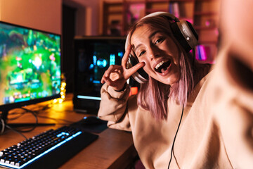 Image of excited girl taking selfie photo while playing video game