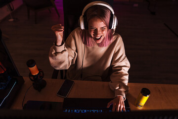 Image of girl making winner gesture and playing video game on computer