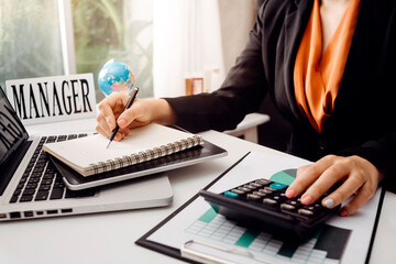 Businesswomen hands working with finances about cost and calculator and laptop with tablet, smartphone at office in morning light