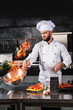 © stockbusters - Chef prepare food with fire at kitchen restaurant. Chef with wok at kitchen.