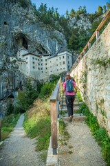 Wall Mural - Hiker couple walking towards the at the Predjama Castle inside the Postojna Cave in Slovenia