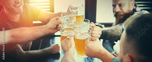 Fotografía Group of friends toasting with beer in pub, closeup