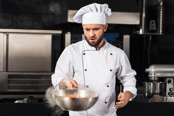 Wall Mural - Chef man prepare food at kitchen restaurant. Serious chef tossing asian food.