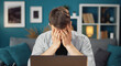 © MYDAYcontent - Tired or exhausted man closing his face with hands sitting in front of computer in living room