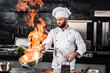 © stockbusters - Chef cook food with fire at kitchen restaurant. Cook with wok at kitchen.