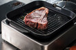 © stockbusters - Steak cooking at griddle pan. Closeup raw beef grill at pan.