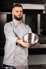 Chef show bowl. Chef man demonstrate clean bowl at professional kitchen.