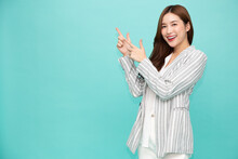 Young Asian Woman Smiling And Pointing Finger To Empty Copy Space Isolated On Green Background