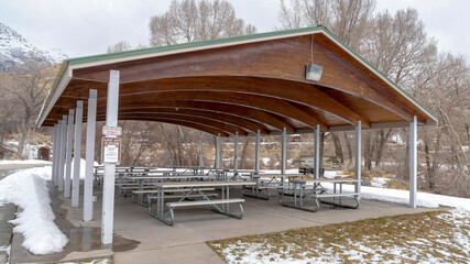 Wall Mural - Panorama crop Pavilion with wooden arches on the ceiling amid park covered with snow in winter