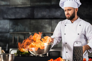 Chef hold wok with fire at kitchen restaurant. Portrait of cook man with wok.