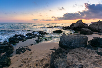 dramatic sunset on the ocean shore. waves crashing rocks on sandy beach. beautiful cloudscape above the horizon