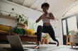 © Prins Productions - Wide angle shot of young female doing home workout or yoga from home, following an online workout on computer or online