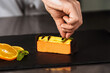 © stockbusters - Chef hands decorate orange cake. Closeup hands decorate dessert with chocolate.