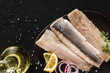 Marinated fillet mackerel or fillet herring fish with spices, greens and slice of bread on plate over dark stone background. Mediterranean food, appetizer, seafood, top view