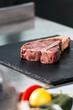 © stockbusters - Raw steak lay at kitchen table. Closeup uncooked beef at kitchen.
