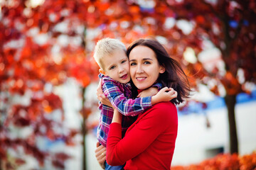 a happy young mother is holding a sweet baby boy, the family is having fun together outside on a nic