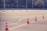 Fototapeta  - Orange cones on the site at a driving school and driving training with the road for students