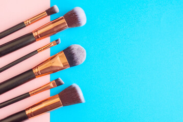 premium makeup brushes on blue and pink background, creative cosmetics flat lay, tools for make up, copy space