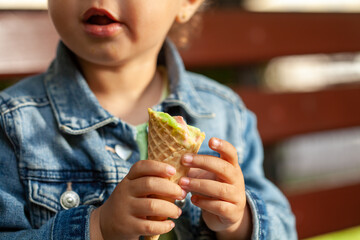 Canvas Print - waffle cone with ice cream in the hands of a child.