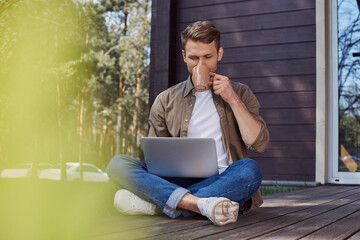 concentrated male working on terrace with a cup of tea